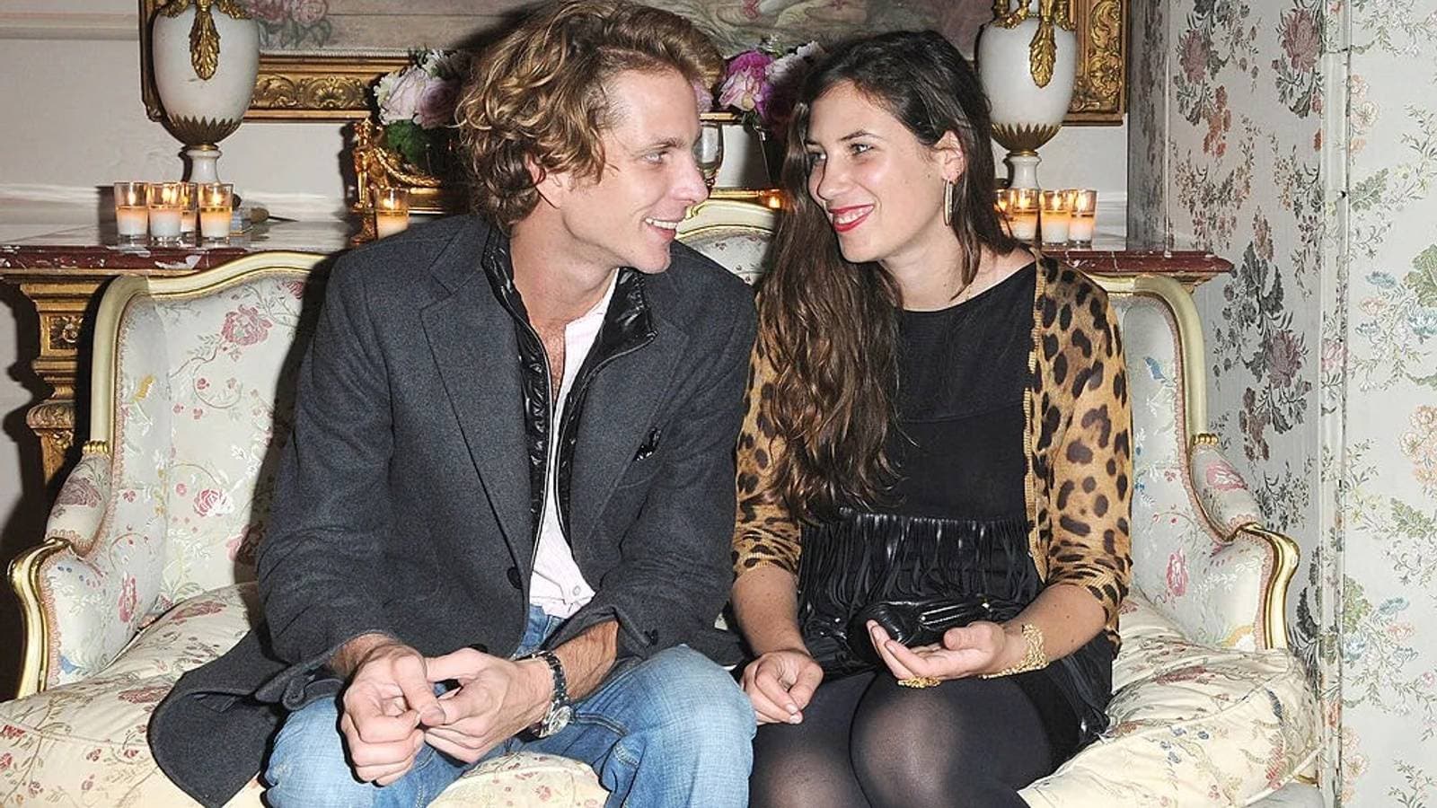 Andrea Casiraghi and Tatiana Santo Domingo seated together on a sofa, smiling at each other in a candlelit room.
