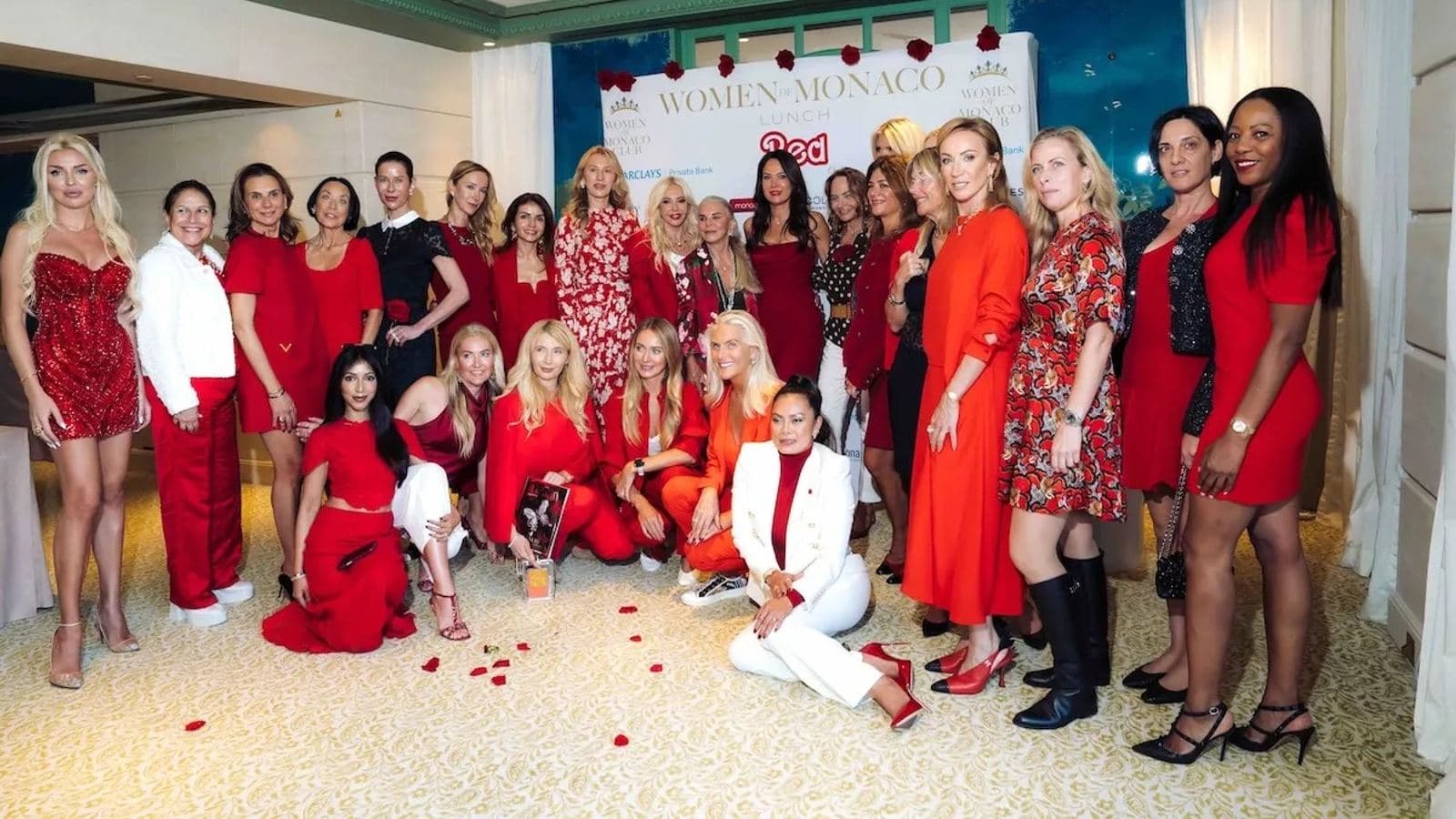 Guests in red outfits posing together at the Women of Monaco Lunch at the Hotel Metropole Monte-Carlo.