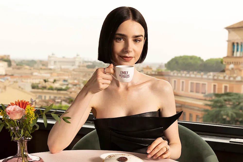 Lily Collins pose avec une tasse à l'effigie d'Emily in Paris sur une terrasse dominant Rome