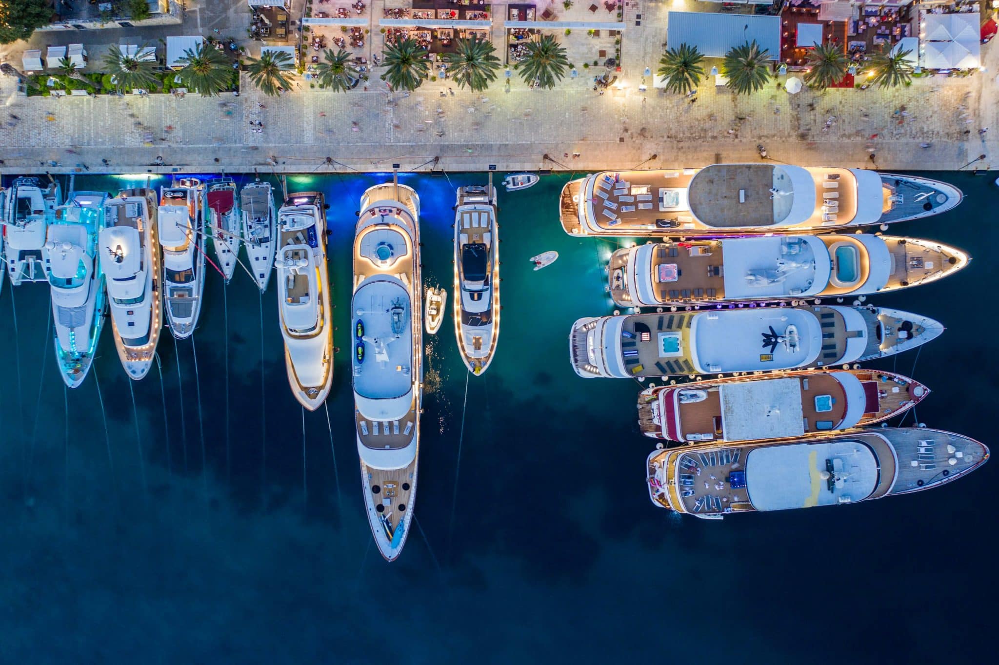 Aerial view of superyachts moored along an illuminated marina at night