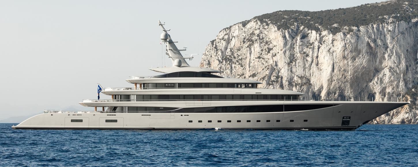 Le superyacht Nixie naviguant le long d'une côte rocheuse